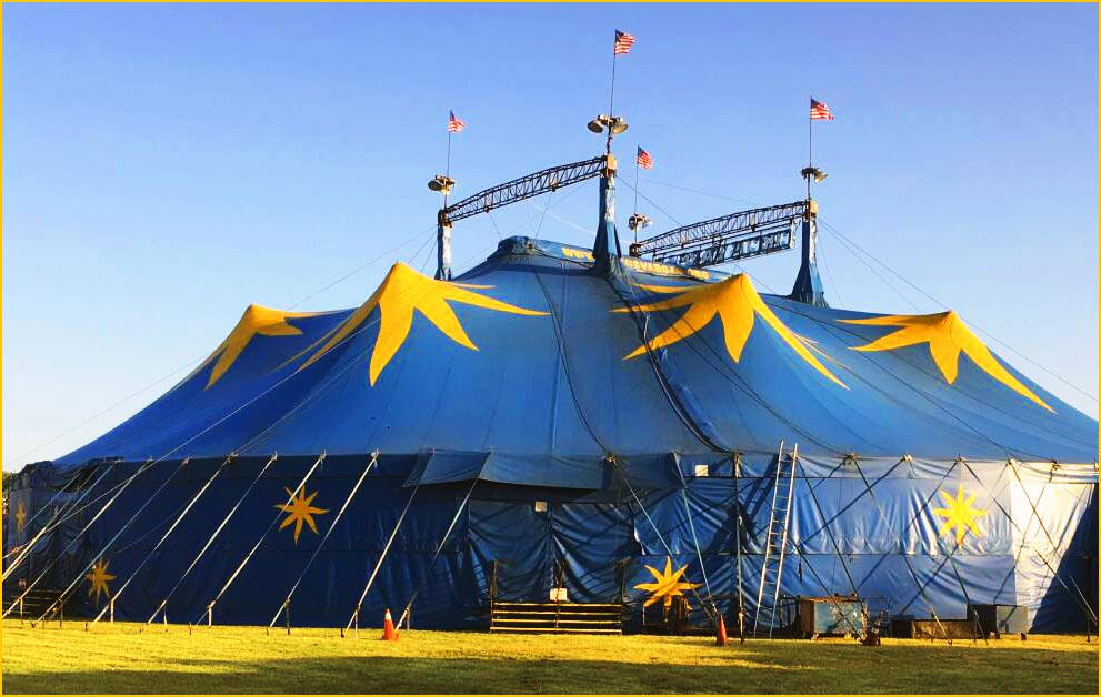 Cirque tent, large blue circus tent with yellow stars in front of a blue sky